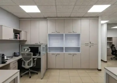 Estación de trabajo y archivo modular con armarios empotrados de piso a techo, nichos abiertos blancos y escritorio esquinero en una oficina.